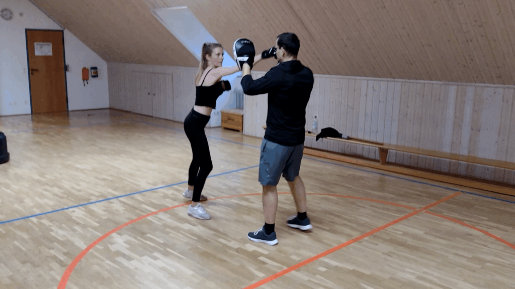Teilnehmerin übt einen Schlag auf die Handpratze ihres Trainingspartners