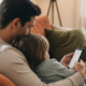 Elternteil und Kind schauen gemeinsam ruhig auf ein Smartphone auf dem Sofa